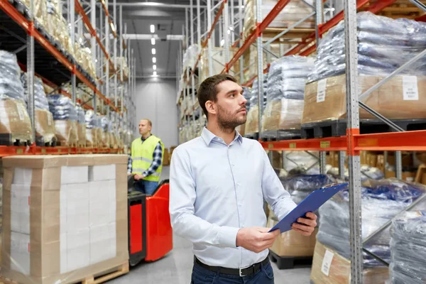 Geschäftsmann und Arbeiter auf Gabelstapler im Lager — Stockfoto