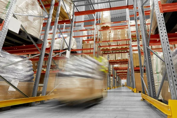 Trabalhador carregando carregador com mercadorias no armazém — Fotografia de Stock