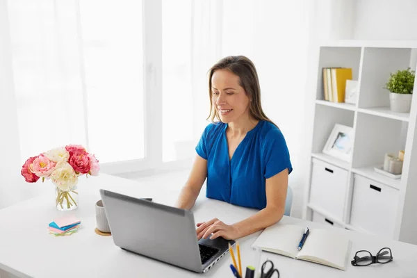 Mujer feliz con el ordenador portátil que trabaja en casa u oficina — Foto de Stock