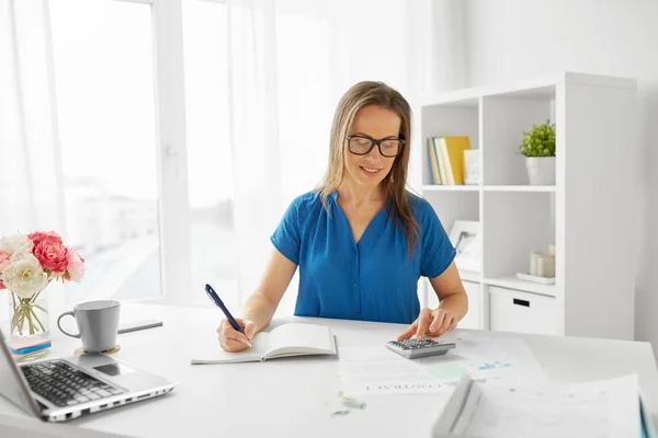 Mujer con calculadora y cuaderno en la oficina —  Fotos de Stock