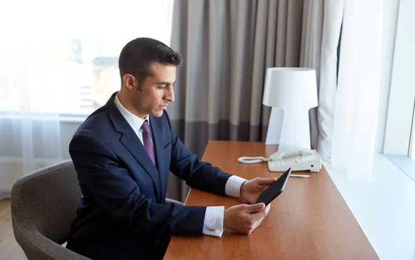 Homem de negócios com tablet pc trabalhando no quarto de hotel — Fotografia de Stock