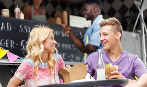 Friends eating and talking at food truck — Stock Photo, Image