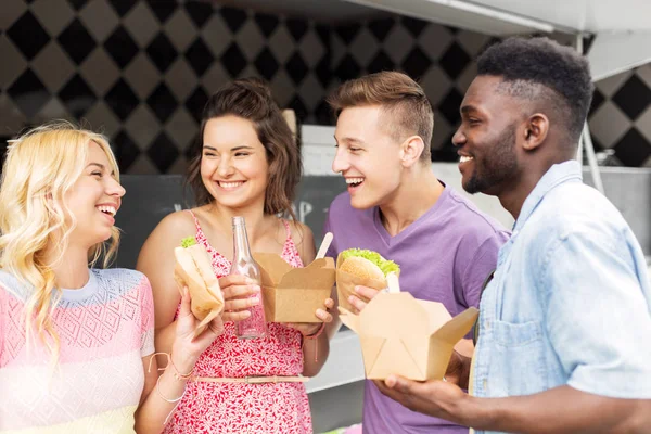 Amis heureux avec des boissons manger au camion de nourriture — Photo