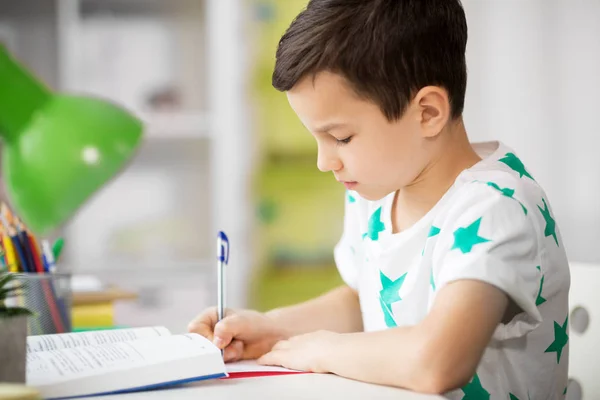 Close up van jongen met leerboek schrijven thuis — Stockfoto