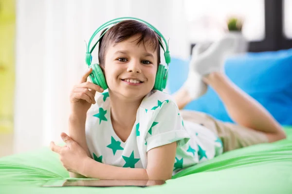 Uśmiechnięty chłopiec z komputera typu tablet i słuchawki w domu — Zdjęcie stockowe