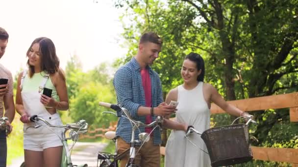 Vrienden met fietsen en smartphones bij park — Stockvideo