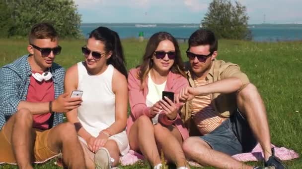 微笑与坐在草地上的智能手机的朋友 — 图库视频影像