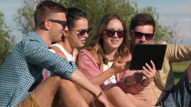 Lachende vrienden met de tablet pc in zomer park — Stockvideo