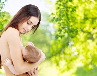 mother breast feeding baby over natural background clipart