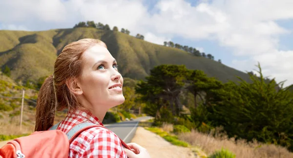 Big sur tepeler üzerinde gülümseyen kadın sırt çantası ile — Stok fotoğraf