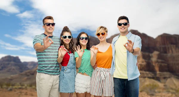 Friends in sunglasses showing ok over grand canyon — Stock Photo, Image