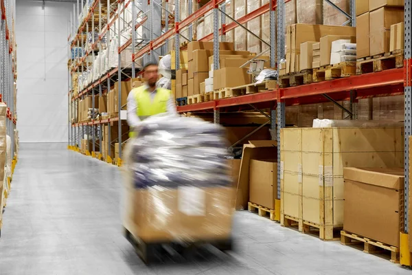 Worker carrying loader with goods at warehouse — Stock Photo, Image