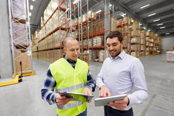 Trabalhador e empresário com tablet pc no armazém — Fotografia de Stock