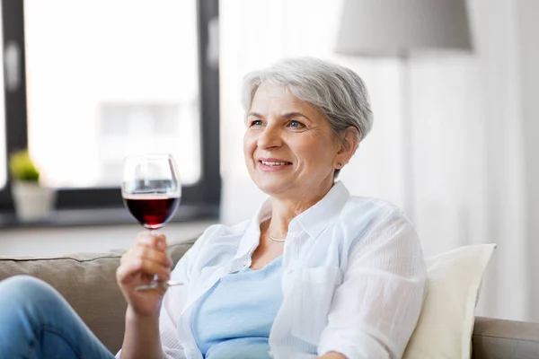 Felice donna anziana con un bicchiere di vino rosso a casa — Foto Stock