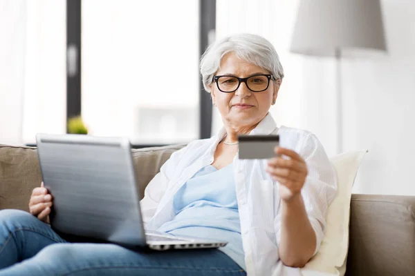 Ηλικιωμένη γυναίκα με φορητό υπολογιστή και πιστωτική κάρτα στο σπίτι — Φωτογραφία Αρχείου