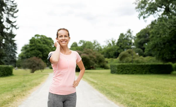 Frau mit Kopfhörer und Armbinde im Park — Stockfoto