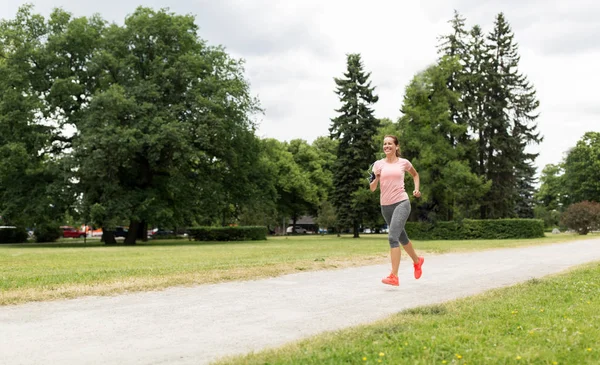 Frau mit Kopfhörern läuft in Park — Stockfoto