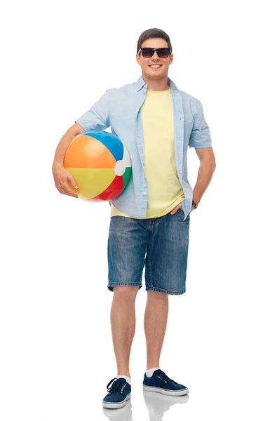 Jeune homme souriant dans des lunettes de soleil avec ballon de plage — Photo