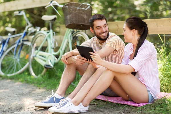 Casal com tablet pc e bicicletas no parque de verão — Fotografia de Stock