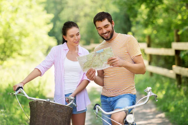 Пара с картой и велосипедами в стране летом — стоковое фото