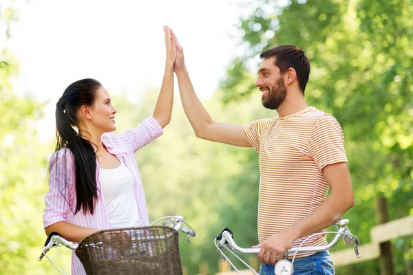 Casal com bicicletas fazendo alta cinco no verão — Fotografia de Stock