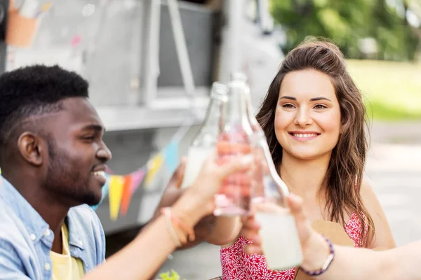 Amigos tintineo botellas con bebidas en camión de comida Imágenes de stock libres de derechos