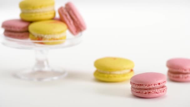 Yellow and pink macarons on glass stand and table — Stock Video