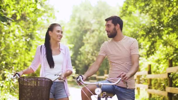 Счастливая пара с велосипедами разговаривает в летнем парке — стоковое видео