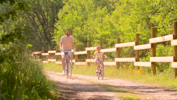 Padre e hija montando bicicletas en el parque de verano — Vídeo de stock