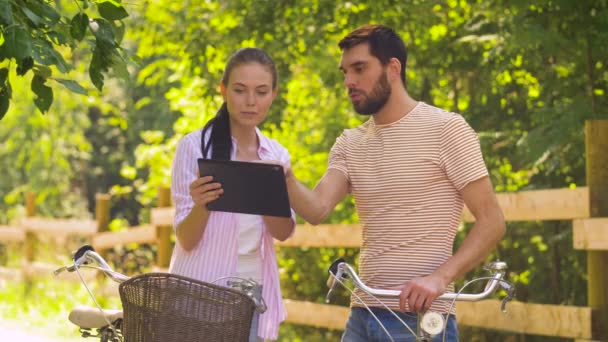 Пара з планшетом і велосипедами в літньому парку — стокове відео