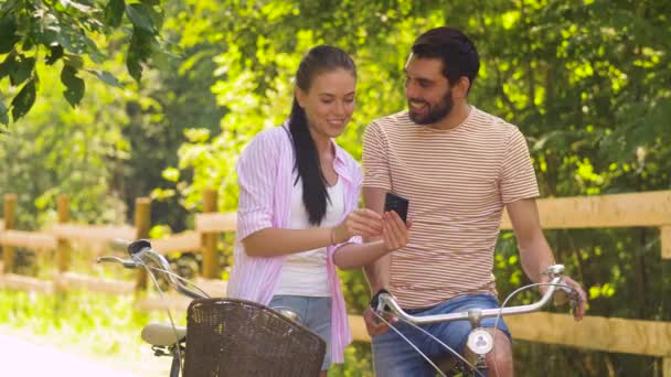 Casal com smartphone e bicicletas no parque de verão — Vídeo de Stock