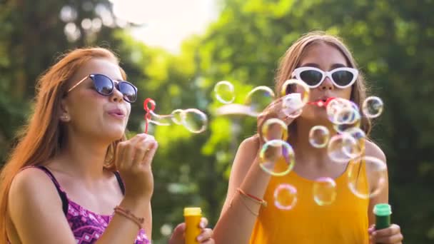 Tienermeisjes waait bubbels in zomer park — Stockvideo