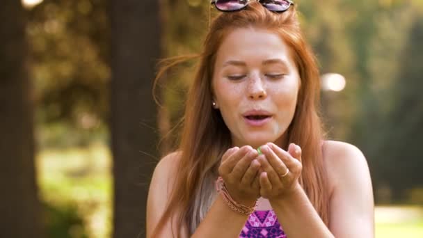 Adolescente chica soplando confeti fuera manos en parque — Vídeo de stock
