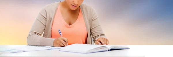 Estudante menina com livro escrito para notebook — Fotografia de Stock