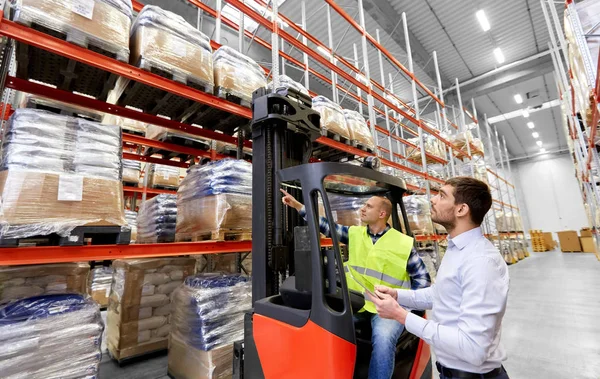 Trabalhador e empresário com tablet pc no armazém — Fotografia de Stock