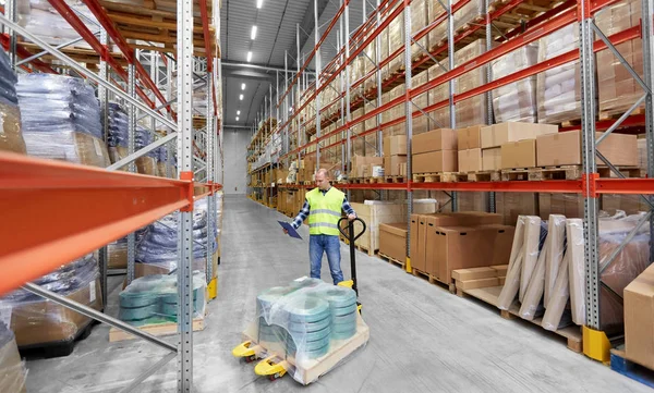 Male worker with loader and clipboard at warehouse — Stock Photo, Image