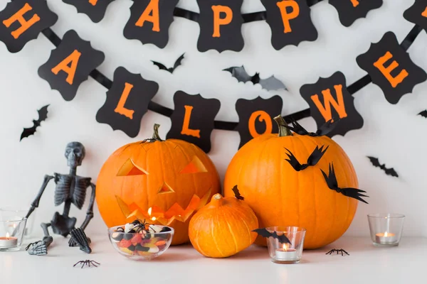 Carved pumpkins with candies and halloween garland — Stock Photo, Image