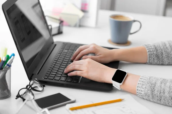 Designer com relógio inteligente e laptop no escritório — Fotografia de Stock
