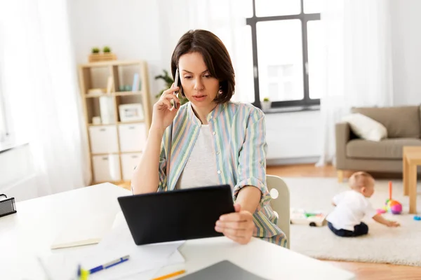 Madre funzionante con tablet che chiama sul cellulare — Foto Stock