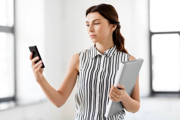 Businesswoman with smartphone and folder at office — Stock Photo, Image
