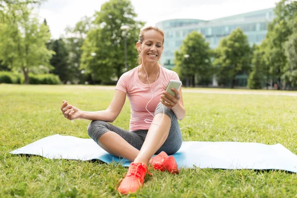 Vrouw met smartphone instellen van muziek voor meditatie — Stockfoto