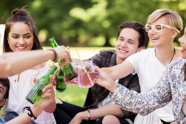 Amigos felizes batendo bebidas no parque de verão — Fotografia de Stock