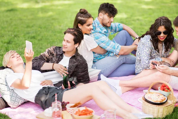 与智能手机的朋友在夏季公园野餐 — 图库照片