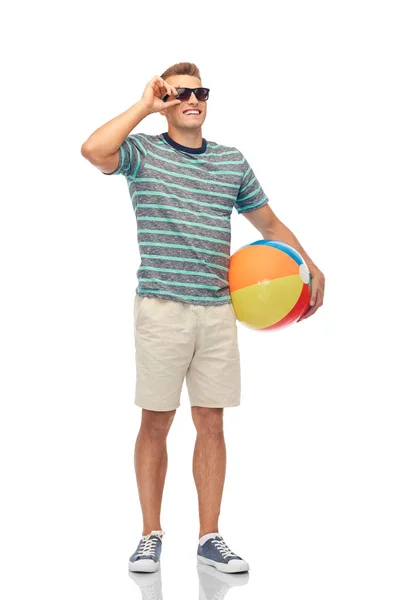 Jovem sorridente em óculos de sol com bola de praia — Fotografia de Stock