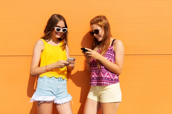 Дівчата-підлітки зі смартфонами влітку на відкритому повітрі — стокове фото