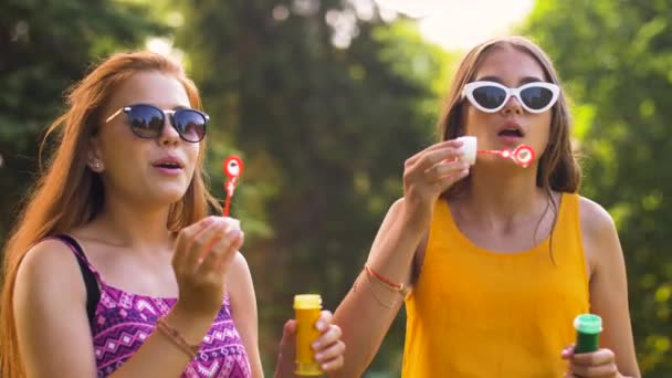 Девочки-подростки пускают пузыри в летнем парке — стоковое видео