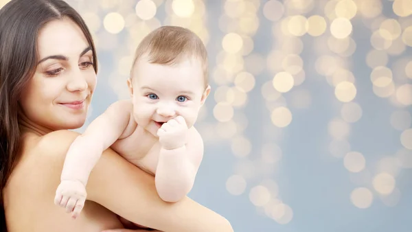 Mãe com bebê sobre luzes festivas fundo — Fotografia de Stock