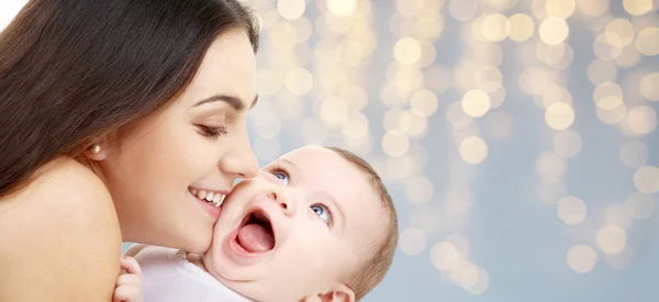 Mãe com bebê sobre luzes festivas fundo — Fotografia de Stock