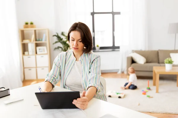 Werkende moeder met tablet pc en baby thuis — Stockfoto