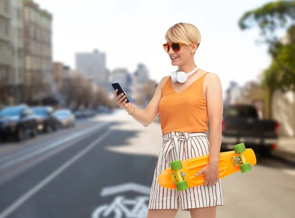 Teenage girl with skateboard and smartphone — Stock Photo, Image